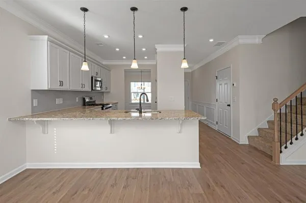 a large kitchen with stainless steel appliances granite countertop a sink a window and a wooden floor
