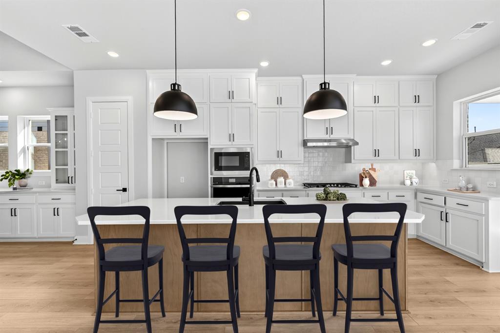 2109 Chance Lane Northlake, TX 76247 - Photo 10 of 36 a kitchen with stainless steel appliances kitchen island granite countertop a dining table chairs and white cabinets