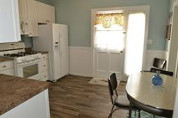 111 Turner Road Scituate, MA 02066 - Photo 9 of 24 a kitchen with stainless steel appliances granite countertop a stove a refrigerator a white table and chairs with wooden floor