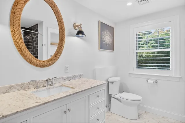 a bathroom with a granite countertop toilet a sink and a mirror