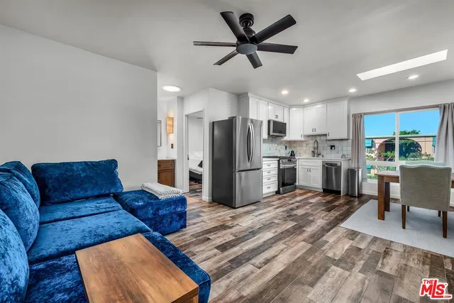a living room with furniture wooden floor and a kitchen view