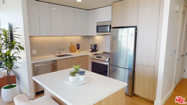 a kitchen with stainless steel appliances a refrigerator a sink a stove a dining table and chairs