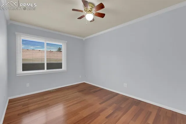 an empty room with wooden floor chandelier fan and windows