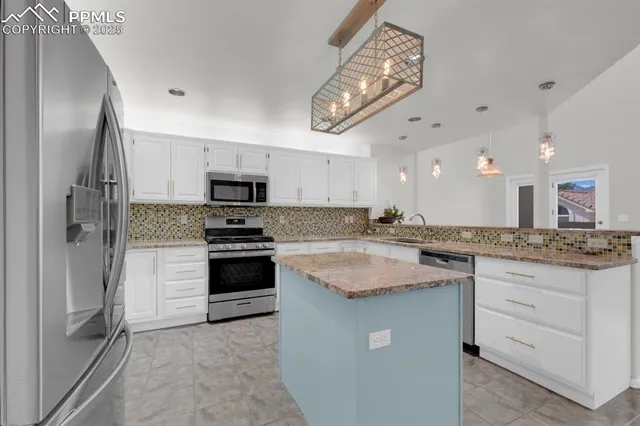 a kitchen with stainless steel appliances granite countertop a stove top oven a sink and a refrigerator