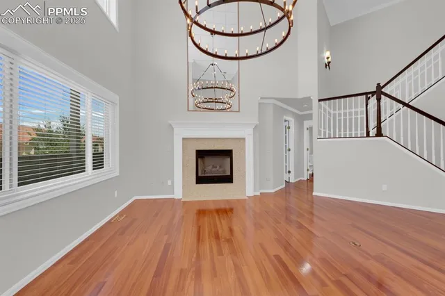 a view of an empty room with wooden floor fireplace and a window