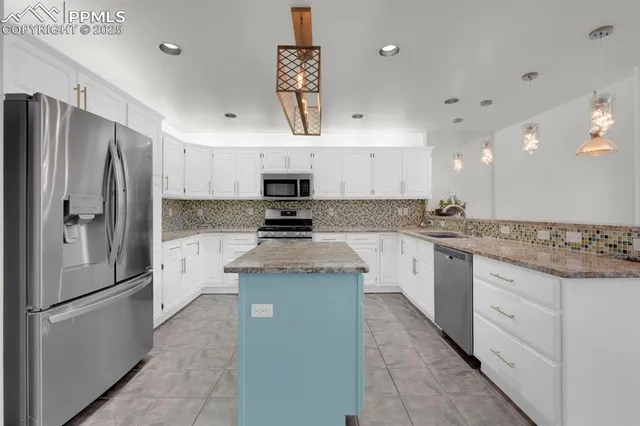 a kitchen with stainless steel appliances granite countertop a refrigerator a sink dishwasher a stove and white cabinets with wooden floor