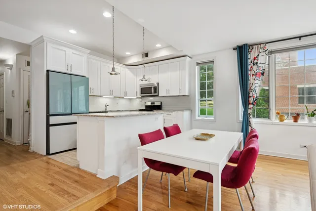 a kitchen with stainless steel appliances kitchen island granite countertop a dining table chairs and a refrigerator