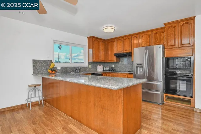 a kitchen with granite countertop a refrigerator stove top oven and sink