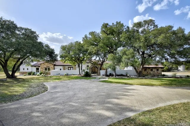 a view of a house with a yard and large trees