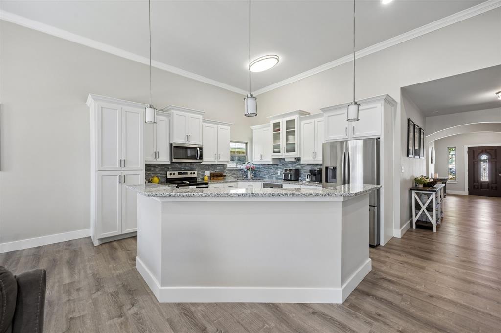 612 Frisco Road Sherman, TX 75090 - Photo 17 of 25 Kitchen featuring white cabinetry, stainless steel appliances, a multi-tone tile backsplash, light-toned countertops, and wood-finish flooring