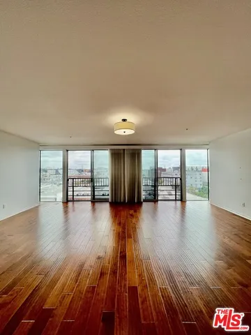 a view of empty room with wooden floor and floor to ceiling window