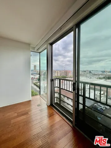 a view of an empty room with wooden floor and a floor to ceiling window