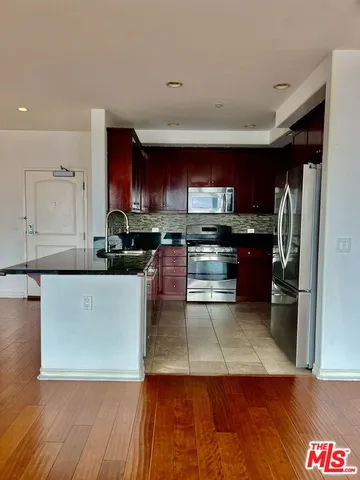 a kitchen with stainless steel appliances granite countertop a refrigerator and a stove top oven