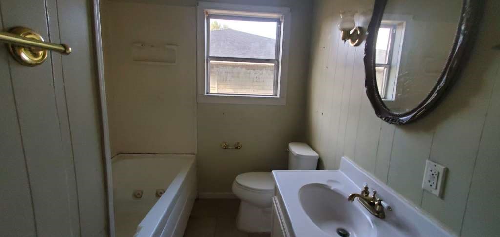6136 25th Street Groves, TX 77619 - Photo 12 of 20 a bathroom with a sink a toilet and a mirror