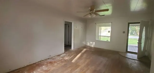 an empty room with windows and fan