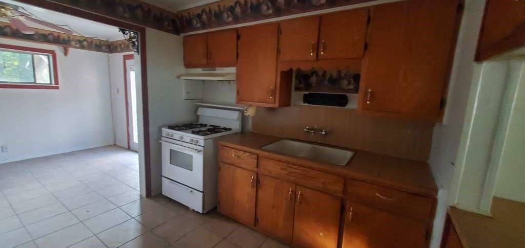 6136 25th Street Groves, TX 77619 - Photo 7 of 20 a kitchen with a refrigerator and a stove