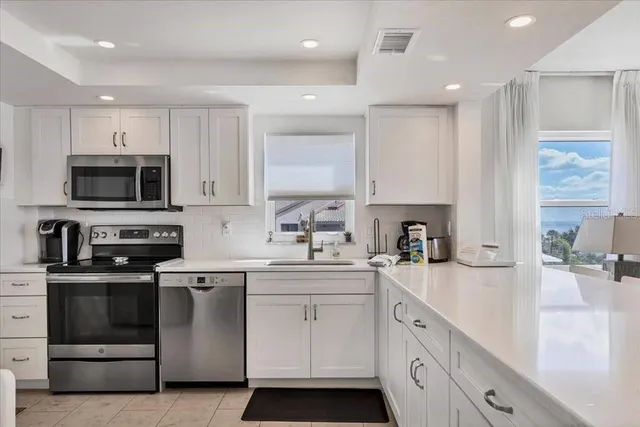 a kitchen with a sink white cabinets and stainless steel appliances