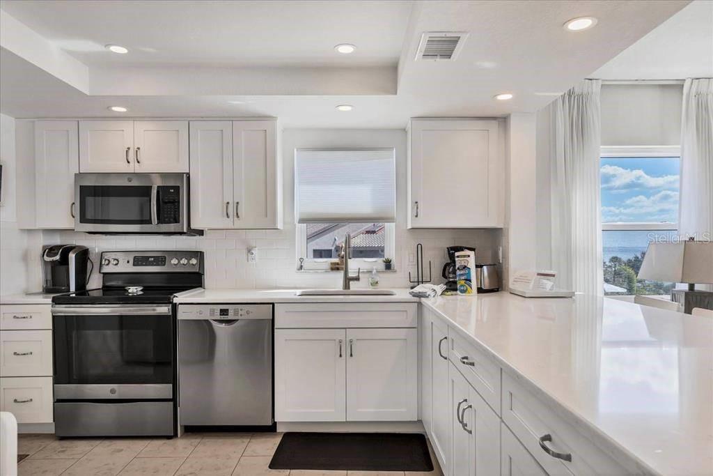 6154 Midnight Pass Road, Unit 301 Sarasota, FL 34242 - Photo 3 of 12 a kitchen with a sink white cabinets and stainless steel appliances