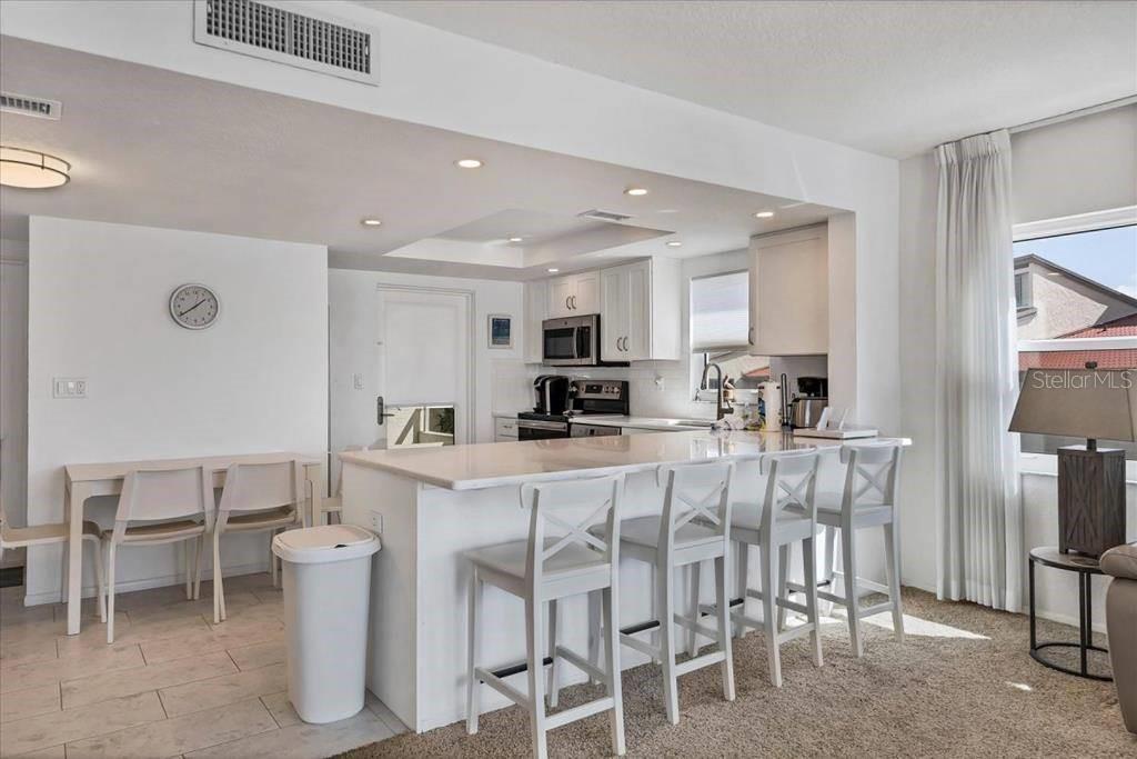 6154 Midnight Pass Road, Unit 301 Sarasota, FL 34242 - Photo 6 of 12 a kitchen with stainless steel appliances kitchen island granite countertop a dining table chairs and a refrigerator