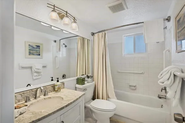 a bathroom with a granite countertop sink a toilet and shower