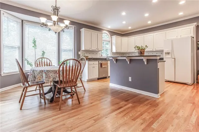 a kitchen with stainless steel appliances granite countertop a refrigerator a stove top oven and a dining table with wooden floor