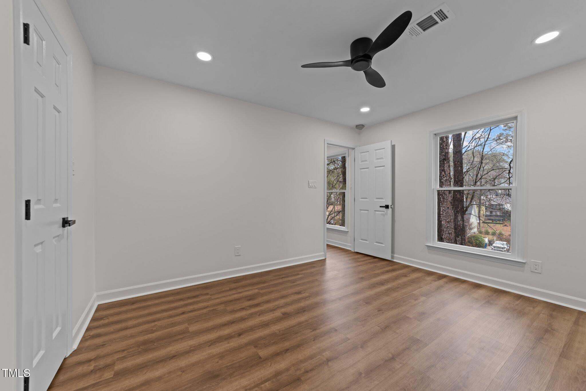 2001 Quail Ridge Road Raleigh, NC 27609 - Photo 29 of 40 an empty room with wooden floor chandelier fan and windows