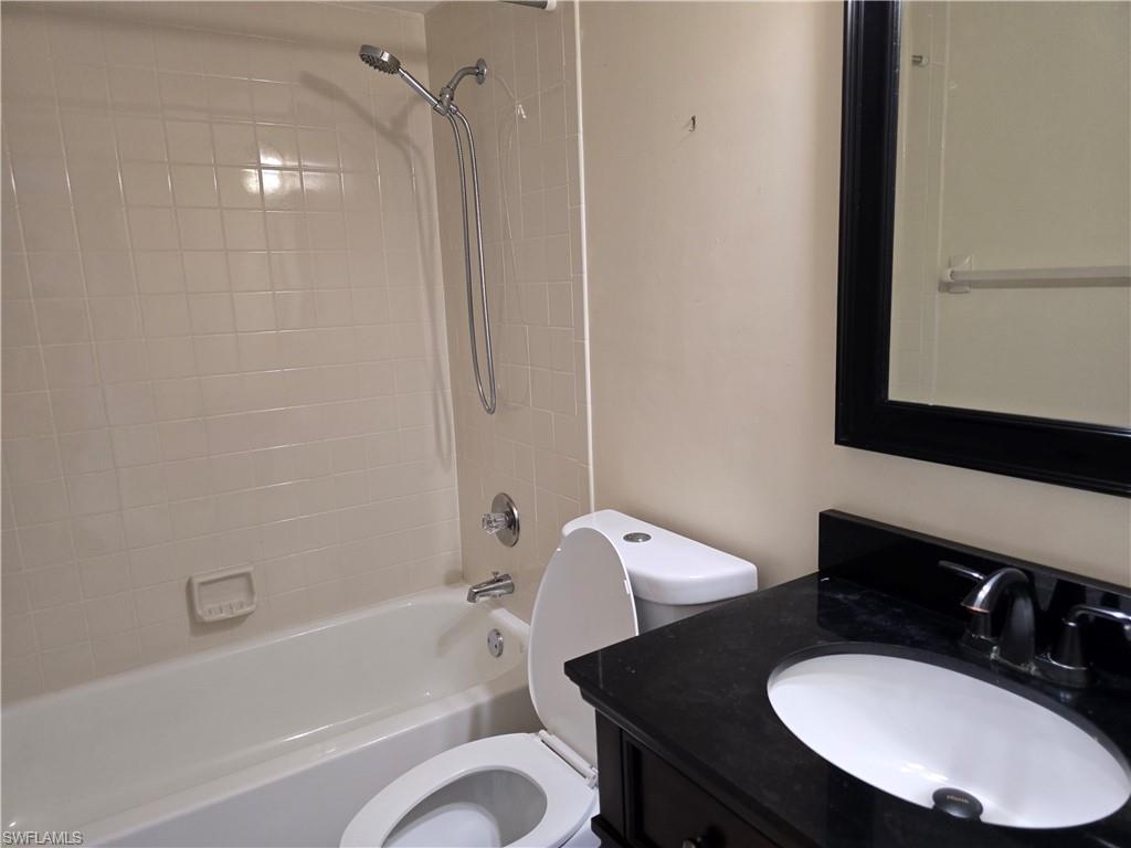 2660 Kings Lake Boulevard, Unit 7103 Naples, FL 34112 - Photo 12 of 22 a bathroom with a sink a toilet a mirror a bathtub and shower
