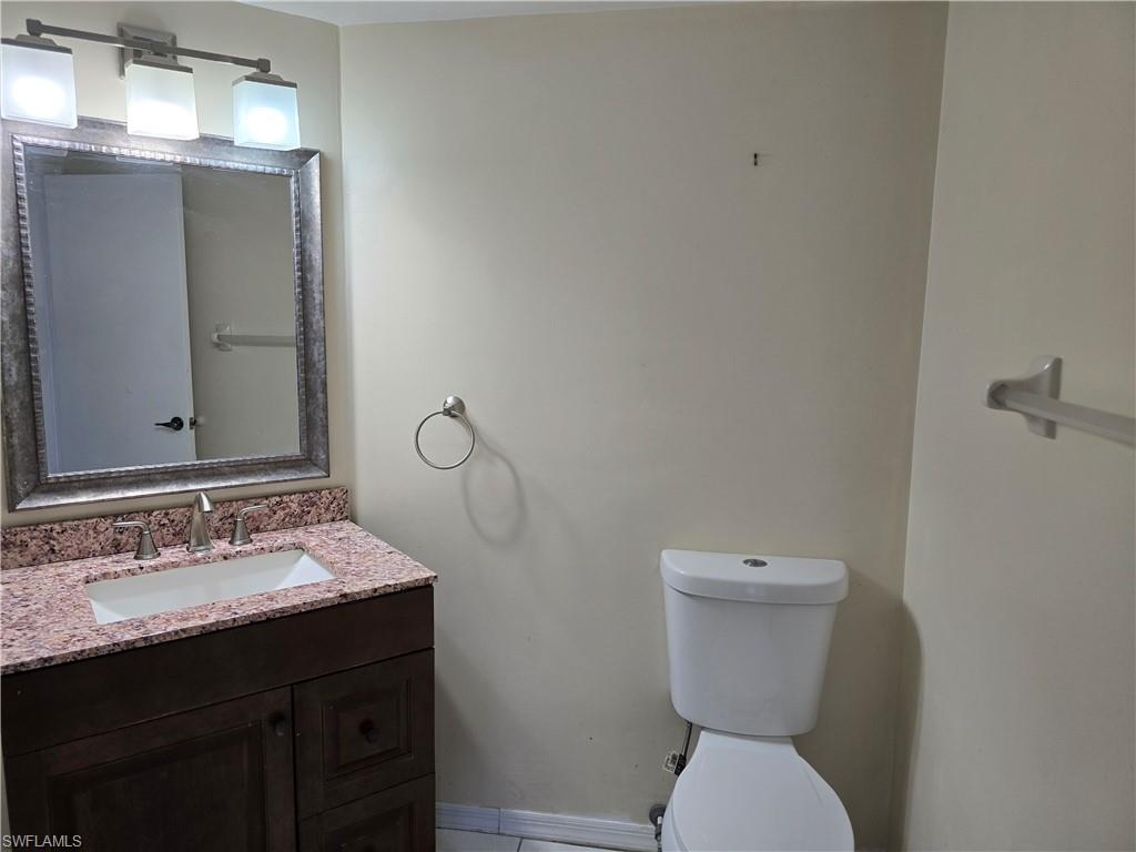 2660 Kings Lake Boulevard, Unit 7103 Naples, FL 34112 - Photo 15 of 22 a bathroom with a toilet sink and mirror