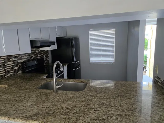 a kitchen with granite countertop a stove a sink and a refrigerator