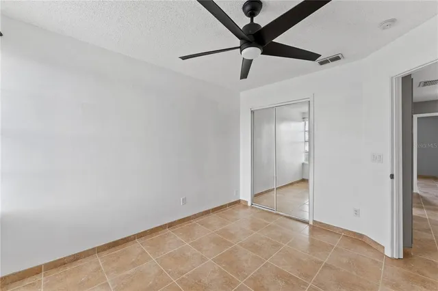 an empty room with a ceiling fan and carpet