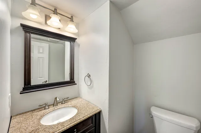 an empty room with wooden floor chandelier and windows