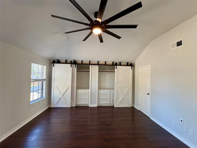 a view of empty room with wooden floor and fan