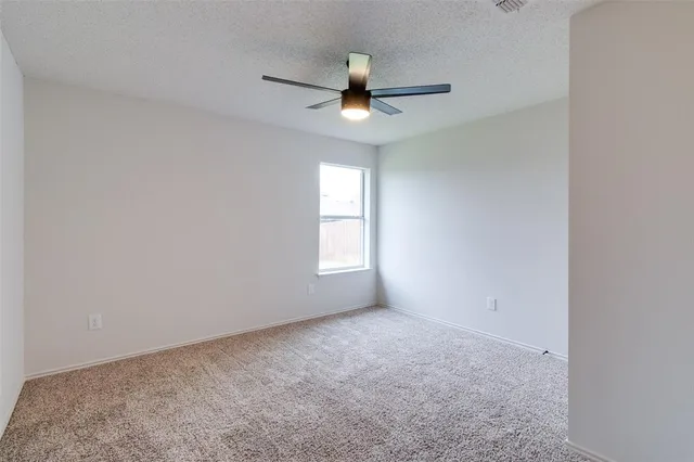 an empty room with a window and a ceiling fan
