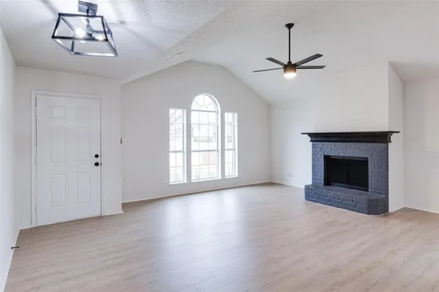 a view of an empty room with chandelier fan and wooden floor