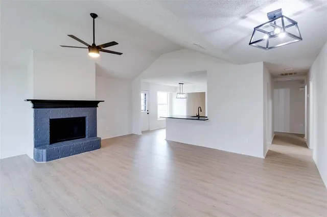 a view of an empty room with a fireplace and wooden floor