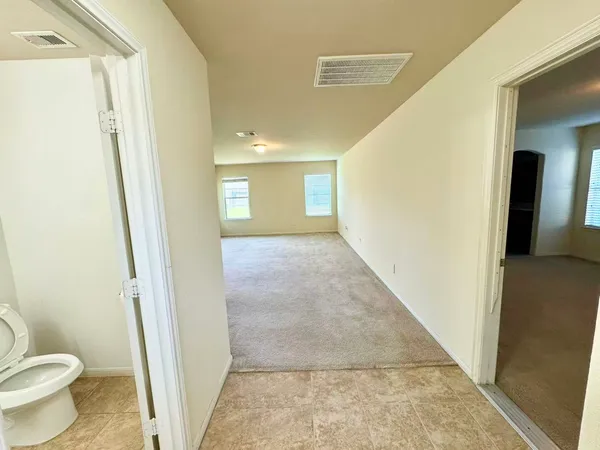 a view of a hallway with wooden floor and a bathroom