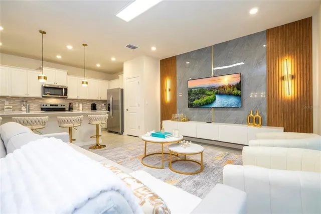 a living room with furniture kitchen view and a wooden floor