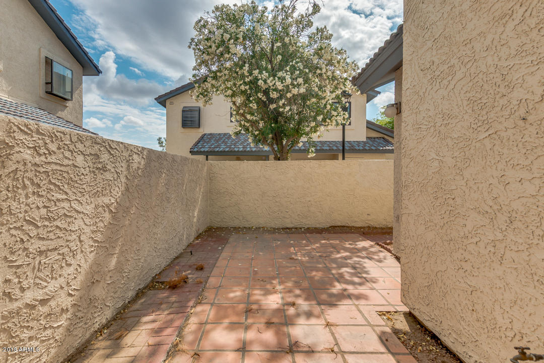 1222 West Baseline Road, Unit 112 Tempe, AZ 85283 - Photo 25 of 26 a view of a yard with a wooden wall and a large tree