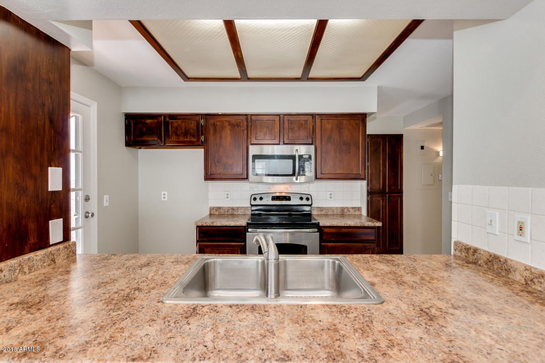 1222 West Baseline Road, Unit 112 Tempe, AZ 85283 - Photo 6 of 26 a kitchen with stainless steel appliances kitchen island granite countertop a stove a sink and a refrigerator