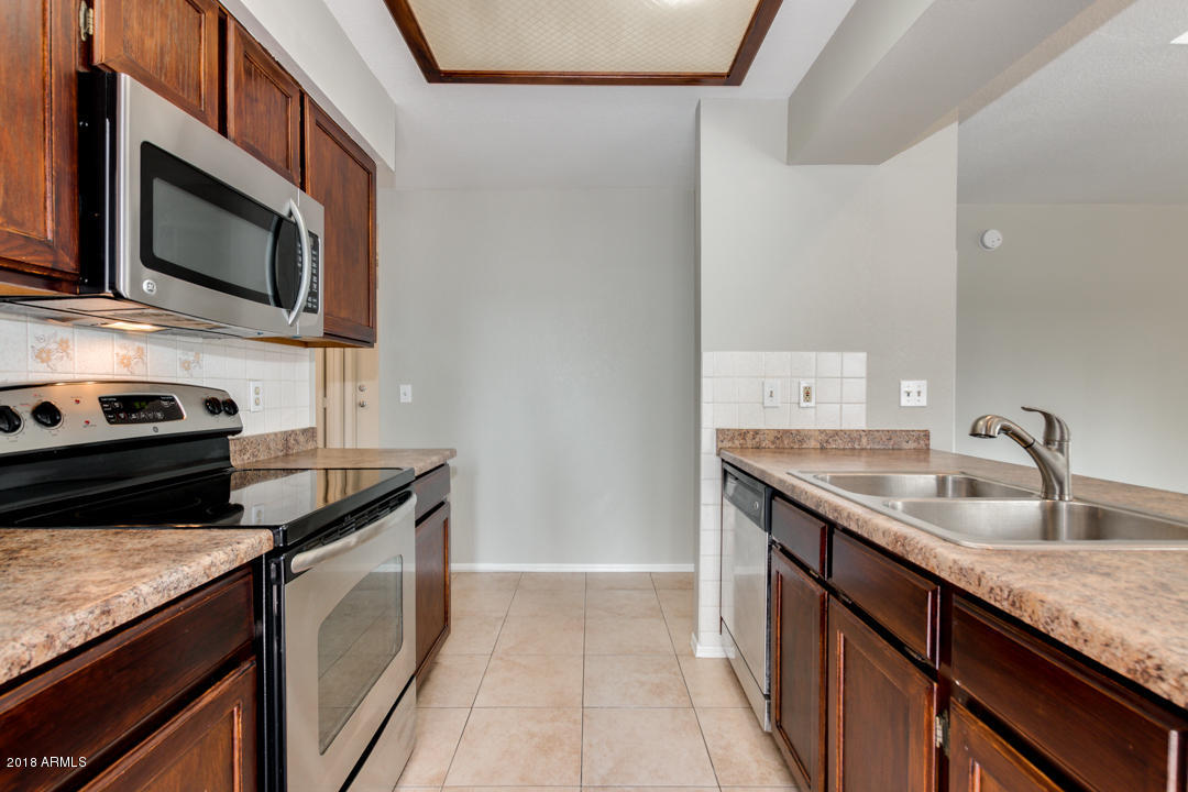 1222 West Baseline Road, Unit 112 Tempe, AZ 85283 - Photo 7 of 26 a kitchen with granite countertop a sink and steel stove