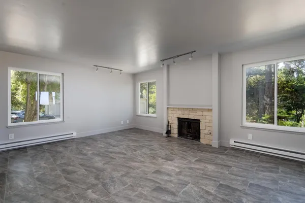 an empty room with windows and fireplace