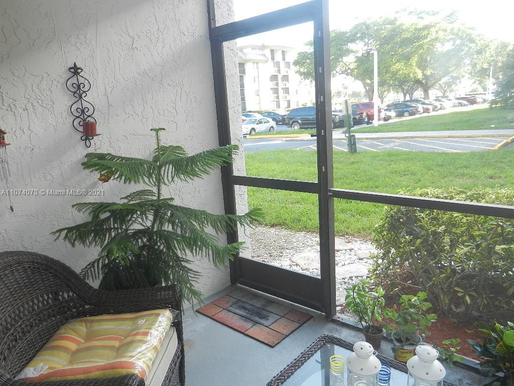 721 North Pine Island Road, Unit 112 Plantation, FL 33324 - Photo 14 of 27 a living room with a floor to ceiling window next to a yard