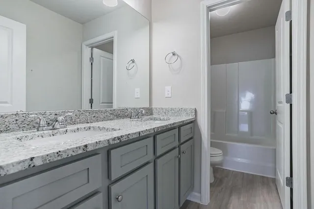 a bathroom with a granite countertop sink a toilet and shower
