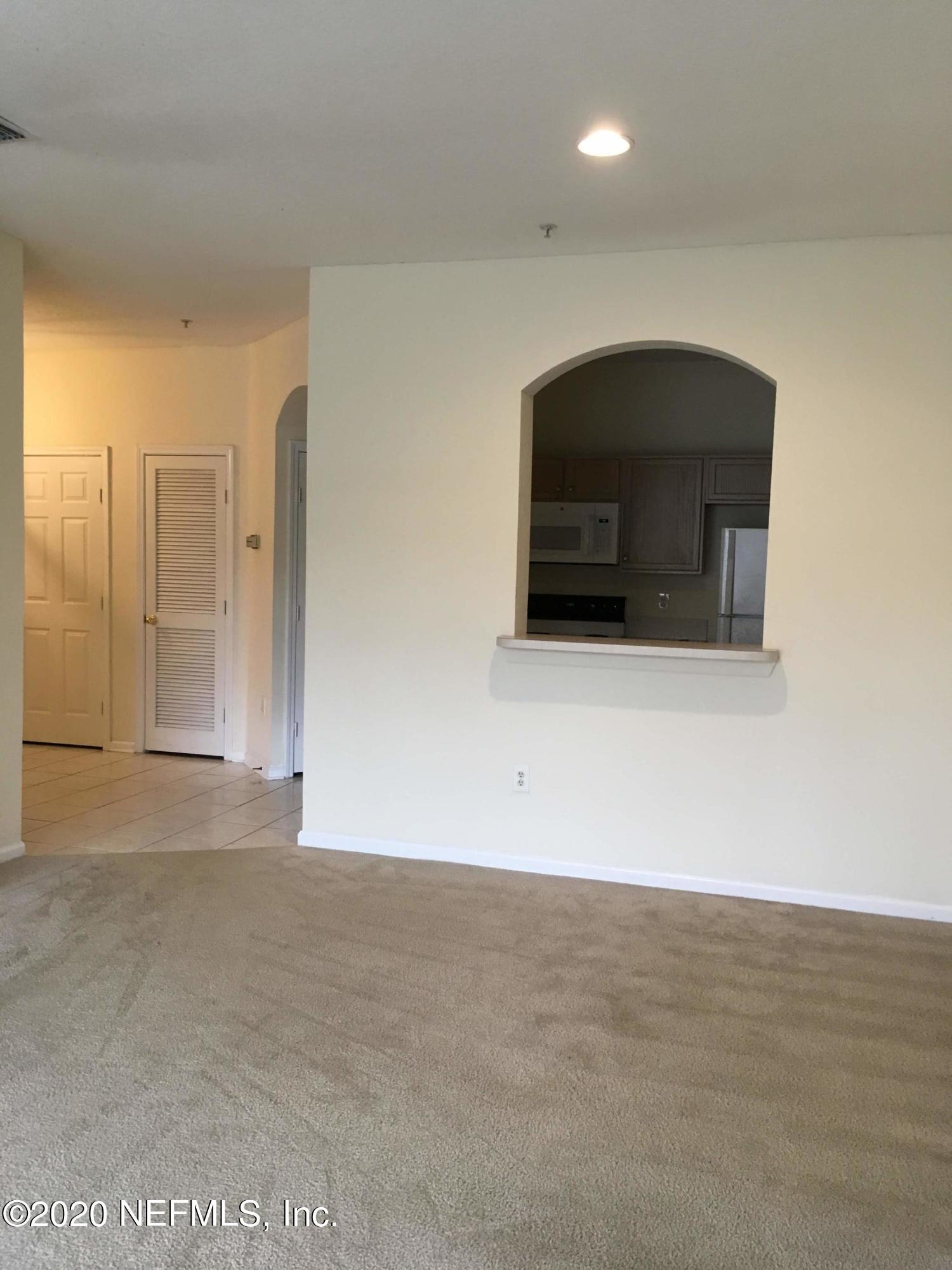 10550 Baymeadows Road, Unit 806 Jacksonville, FL 32256 - Photo 11 of 30 a view of an empty room with wooden floor and a kitchen