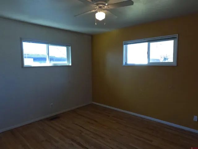 an empty room with wooden floor and windows