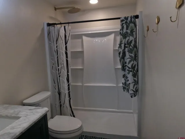 a bathroom with a granite countertop toilet and a shower
