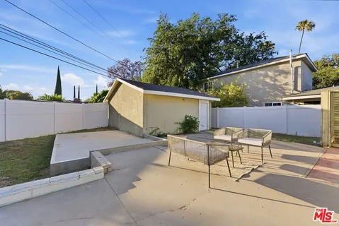 a view of a backyard with potted plants and a large tree