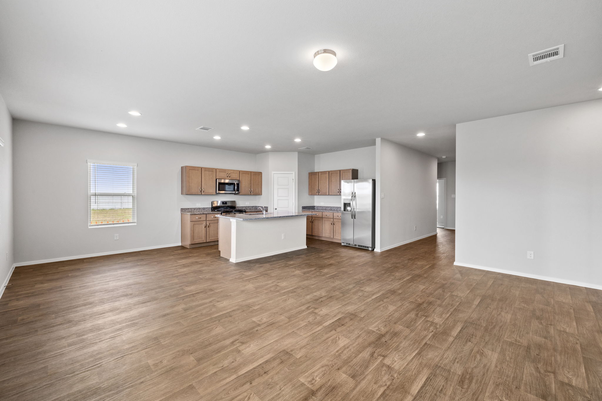 2460 Winding Creek Road Kyle, TX 78640 - Photo 10 of 20 An open-concept living space integrates a well-appointed kitchen with warm wooden floors.