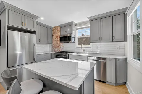 a kitchen with stainless steel appliances granite countertop a sink a stove a refrigerator cabinets and a counter top space