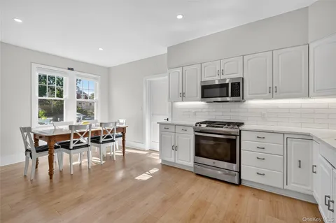 a kitchen with stainless steel appliances a white stove top oven table and chairs